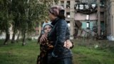 Vera (8 ani) și mama sa Olga în fața unei școli distruse din regiunea Donețk, 13 octombrie 2022.