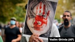 Një protestues në Bukuresht mban portretin e Mahsa Aminit. 
