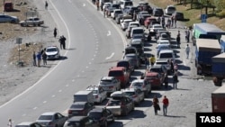 Люди и автомобили на дороге в сторону КПП "Верхний Ларс" на российско-грузинской границе после объявленной мобилизации