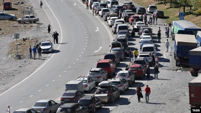 Люди и автомобили на дороге в сторону КПП "Верхний Ларс" на российско-грузинской границе после объявленной мобилизации