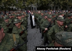 Священник благословляет призывников, прошедших частичную мобилизацию в России, перед их отъездом в Севастополь, Крым, 27 сентября 2022 года