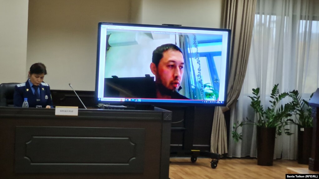 Дистанционно участвующий в суде активист Альнур Ильяшев на экране и прокурор в зале суда. 17 октября 2022 года