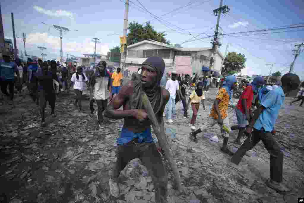 Un protestatar poartă o bucată de lemn care simulează o armă în timpul unui protest care cere demisia premierului Ariel Henry, în zona Petion-Ville din Port-au-Prince, Haiti, la 3 octombrie 2022.&nbsp; Foto: AP Photo/Odelyn Joseph