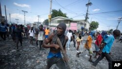 Demonstrant nosi komad drveta koji simulira oružje tokom protesta koji zahtjeva ostavku premijera Ariela Henrija, u oblasti Petion-Ville u Port-o-Prensu, Haiti, ponedeljak, 3. oktobra 2022. 