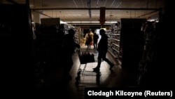 People shop in a supermarket in the dark in Kharkiv on October 17 amid Russia's shelling of power stations and electricity facilities. 