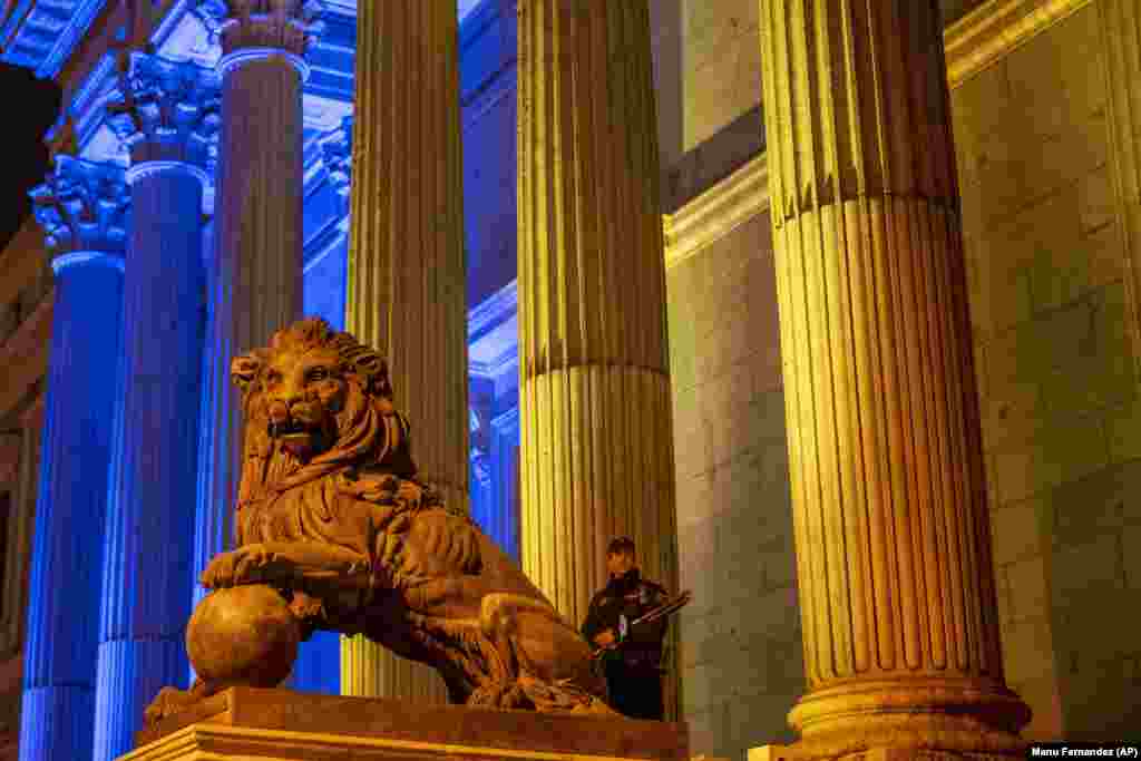 A policeman and bronze lion guard the Spanish parliament in Madrid on March 1.&nbsp;
