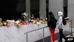 Tinejdžeri gledaju u bukete cvijeća izložene na ulazu u zgradu u kojoj je živjela Lola, Pariz, 17. oktobar 2022.