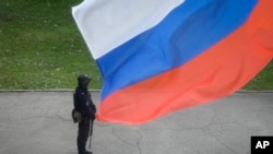 A Russian policeman stands guard at a polling station beneath a Russian flag in Ukraine's Luhansk region on September 27. 