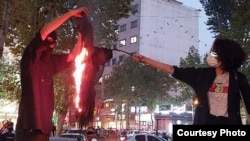 A woman sets fire to a headscarf in Iran during a recent protest.