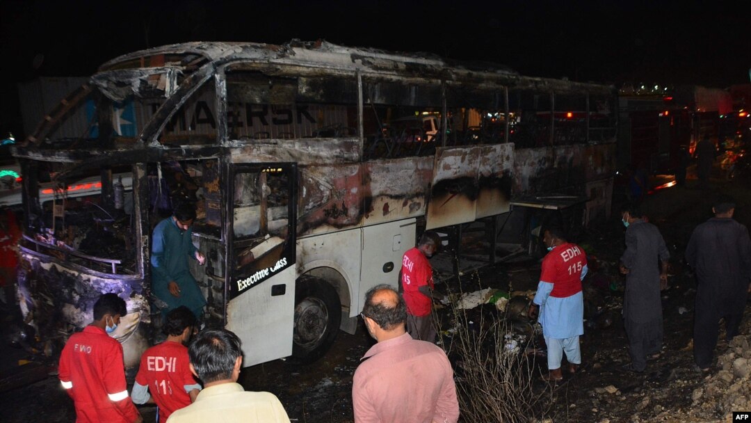 Volunteers search the remains of a passenger bus after it was engulfed by fire on the M-9 motorway in the Nooribad area of the Jamshoro district in Sindh Province early on October 13.