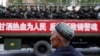 China-FILE PHOTO: A Uighur man looks on as a truck carrying paramilitary policemen travel along a street during an anti-terrorism oath-taking rally in Urumqi, Xinjiang Uighur Autonomous Region, China May 23, 2014. The Chinese characters on the banner read