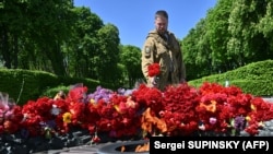 A Ukrainian soldier lays flowers at the Monument to the Unknown Soldier during Victory Day in Kyiv on May 9, 2022.