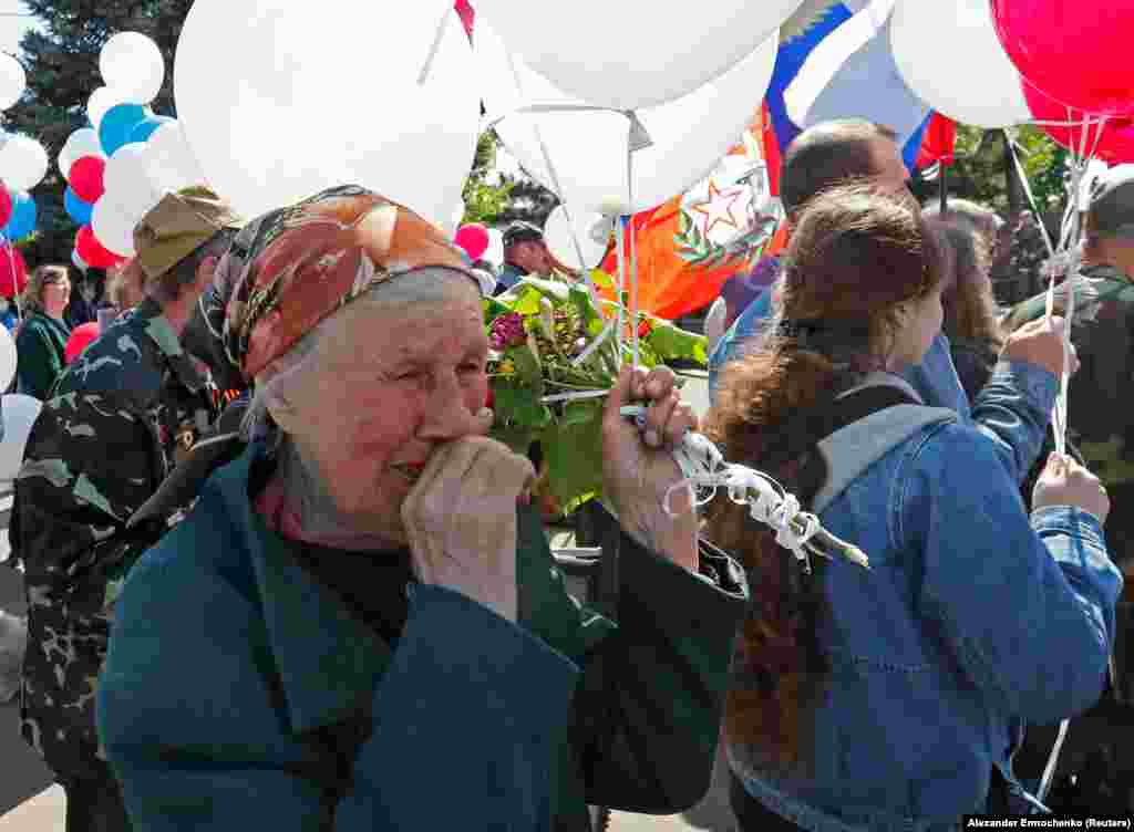 Clutching white balloons, an elderly woman watches the celebration in Mariupol. Mayoral aide Petro Andryushchenko wrote on his Telegram channel that elderly people were recruited to participate.&nbsp;