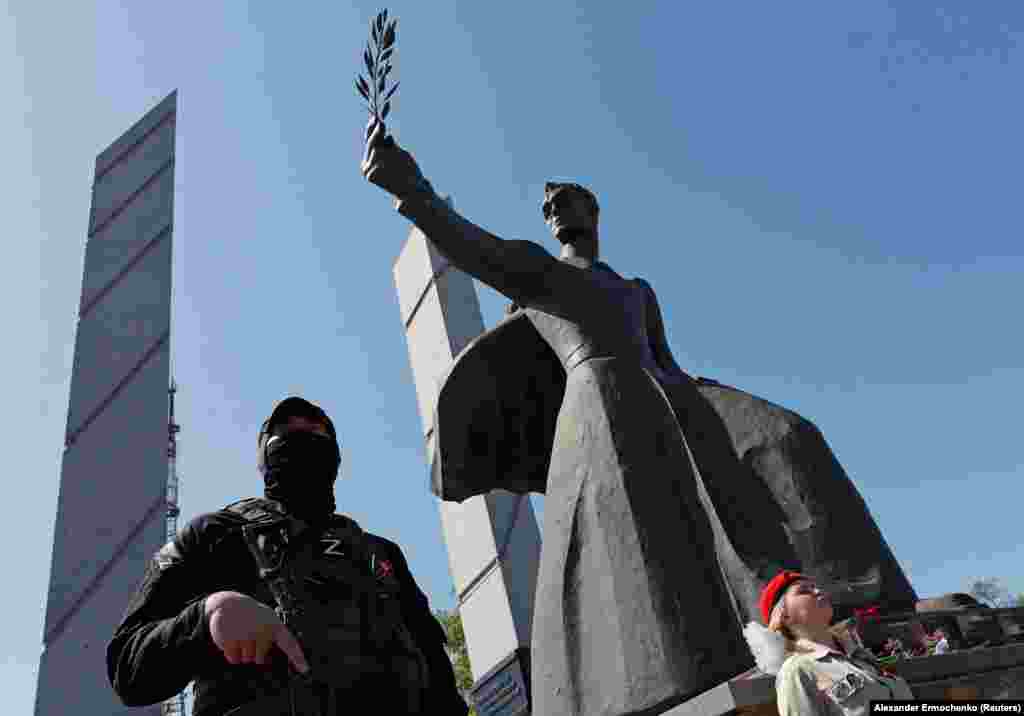Një luftëtar separatist duke vëzhguar turmën nën Memorialin e Çlirimit në Mariupol.