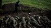 A member of a demining team checks for explosives around the bodies of 11 Russian soldiers in the village of Vilkhivka, near Kharkiv, which was recently retaken by Ukrainian forces.