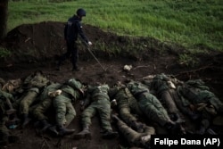 A member of a Ukrainian demining team checks for explosives around the bodies of 11 Russian soldiers in the village of Vilkhivka, which was retaken by Ukrainian forces, near Kharkiv on May 9.