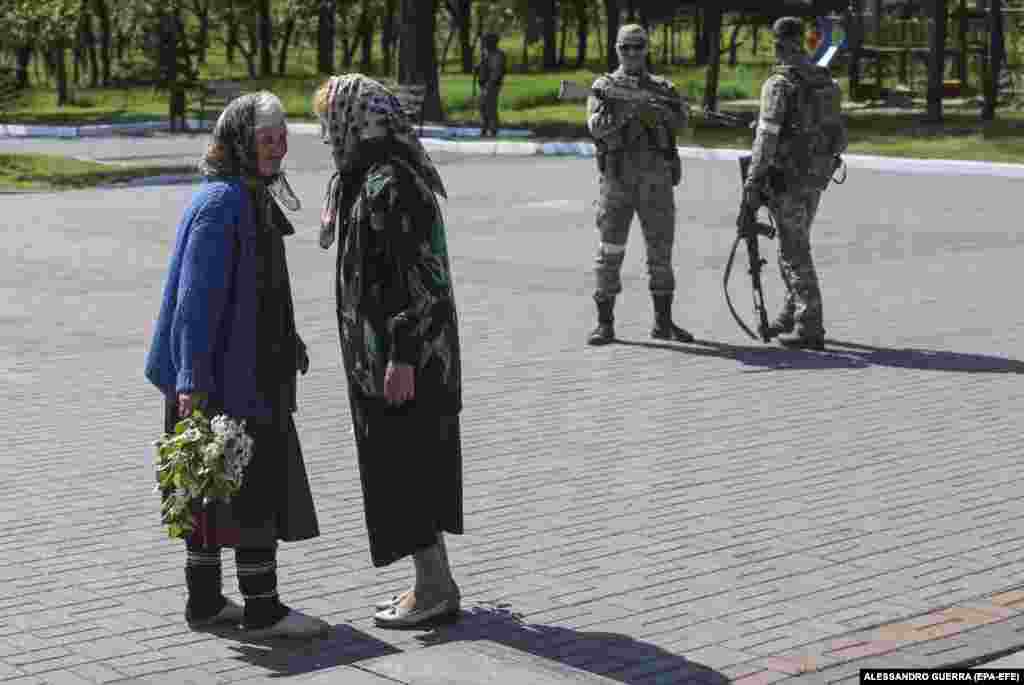 Local women talk as separatist troops stand guard.