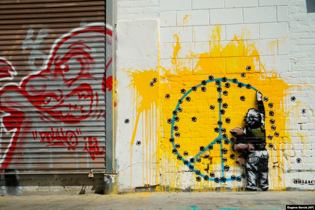 A child paints anti-war graffitti on a wall