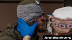 A nurse cleans blood from a volunteer soldier who was injured by shrapnel during combat in Popasna at a hospital in Bakhmut in the Donetsk region in May.