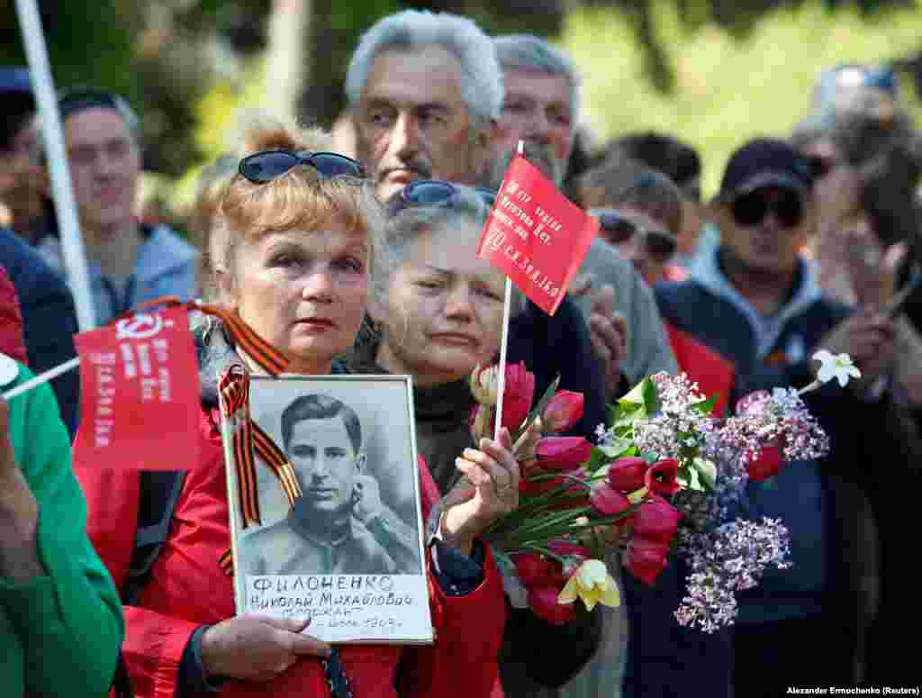 O femeie ține în mână un portret al unui soldat al Armatei Roșii, la care a fost agățat simbolul invaziei rusești în Ucraina.