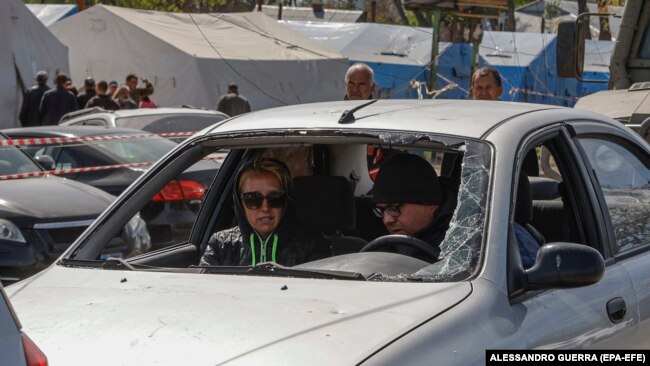 Banorët e Mariupolit presin në një pikë kontrolli në automjetin e tyre të dëmtuar, maj 2022.