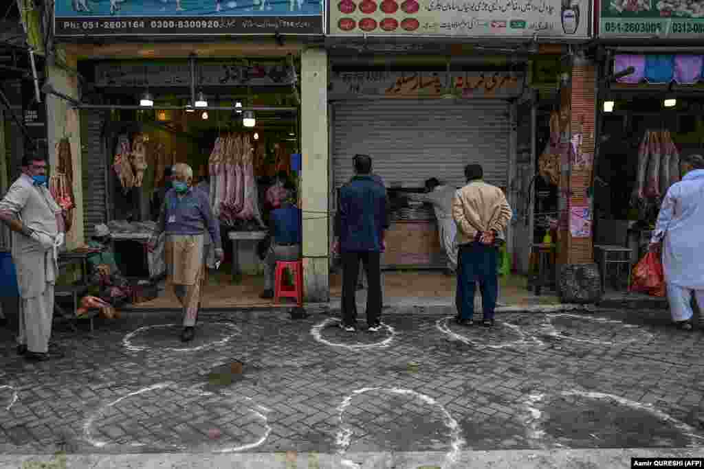 Покупатели стоят в очерченных на земле кружках рядом с мясным и продуктовым магазинами. Исламабад, 25 марта 2020 года. Правительство Пакистана рекомендовало жителям держаться на расстоянии друг от друга в качестве меры профилактики коронавируса.