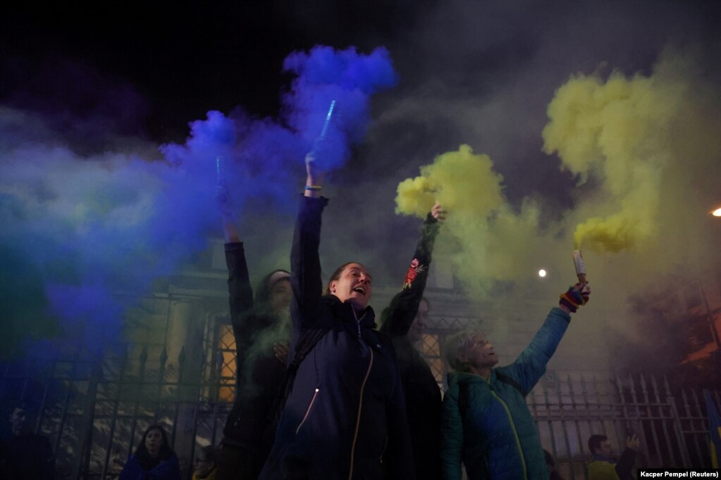 Protestuesit mbajnë në duar flakë me ngjyrat e flamurit ukrainas jashtë ambasadës ruse në Varshavë, pas valës së sulmeve raketore të Rusisë në Ukrainë, më 10 tetor.