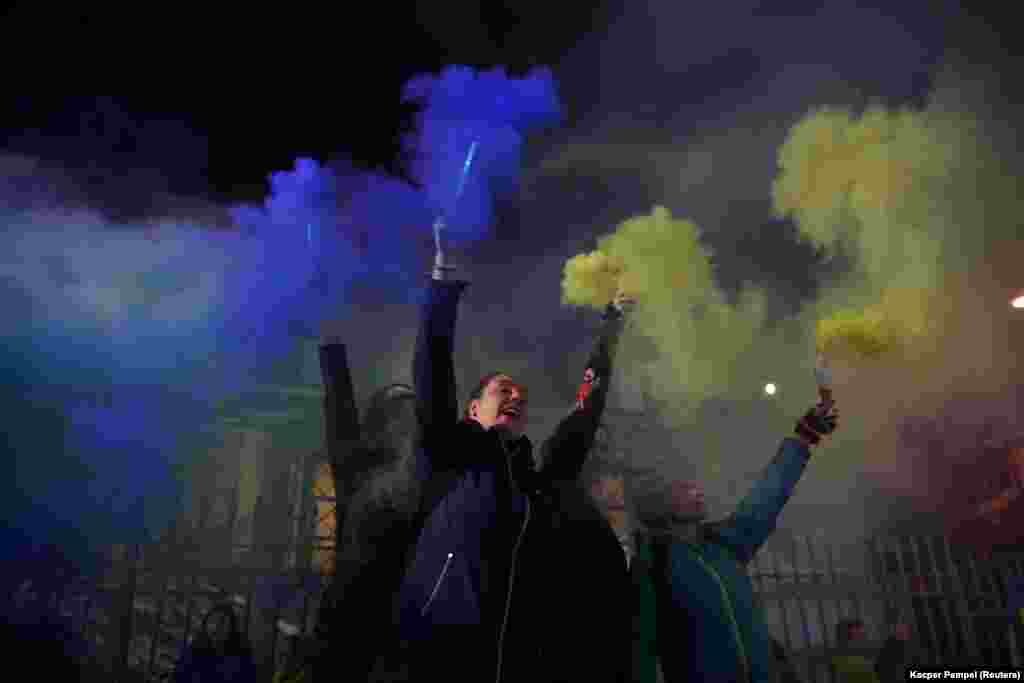 Protesters hold up flares in the Ukrainian colors outside the the Russian Embassy in Warsaw after Russia&#39;s wave of missile strikes in Ukraine on October 10.