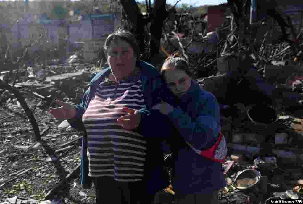 Дівчинка тулиться до бабусі. Вони стоять біля свого будинку, зруйнованого обстрілами, 17 жовтня 2022 року &nbsp;