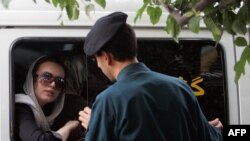 An Iranian morality policeman (right) speaks with a woman siting in a police car after she was arrested because of her "inappropriate" dress in Tehran. (file photo)