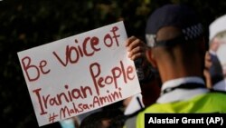 Demonstranți cu pancarte pe care scrie „Fii vocea poporului iranian! #Mahsa Amini” în fața ambasadei Iranului din Londra, 25 septembrie 2022