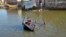 A girl sits on a cot as she crosses a flooded street in Balochistan Province on October 4.