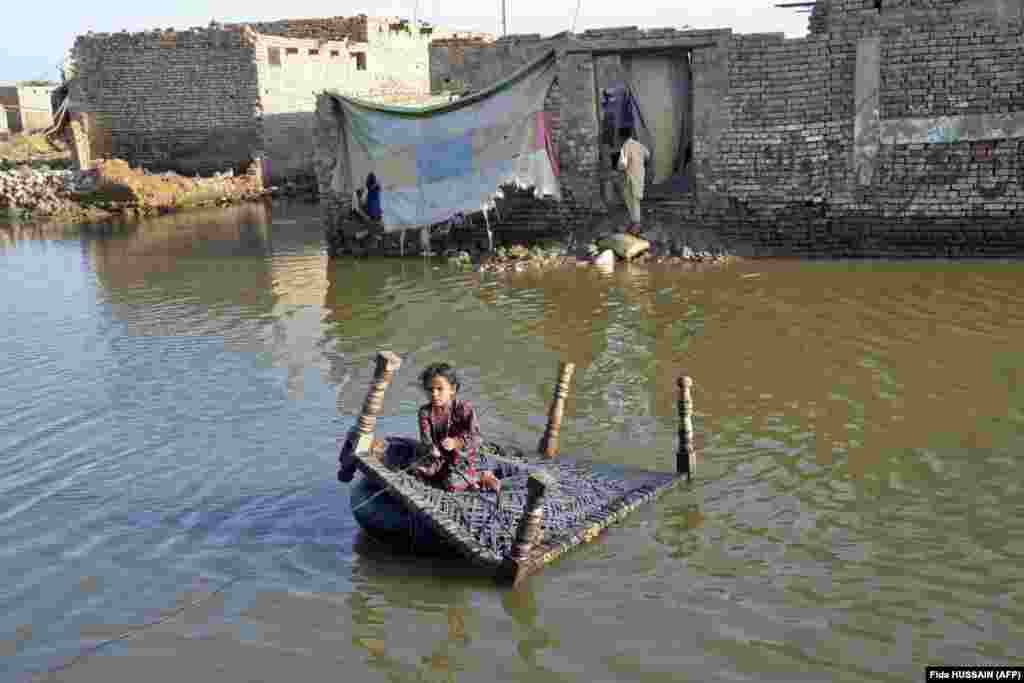 A girl sits on a cot as she crosses a flooded street in Sohbatpur in the Jaffarabad district of Pakistan&#39;s Balochistan Province.&nbsp;