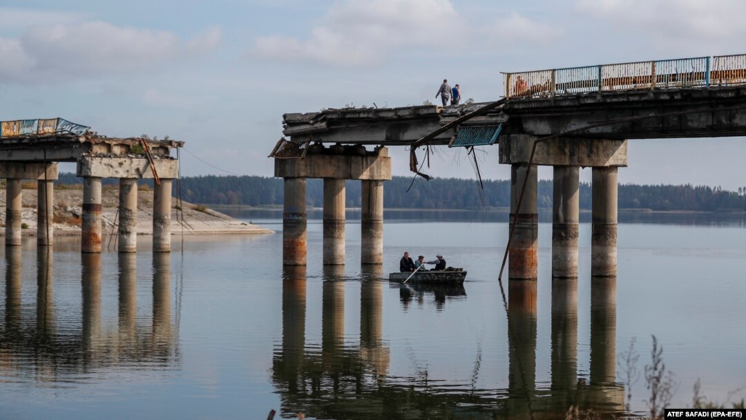 Civilians cross the Siverskiy Donets River by boat under a damaged bridge in the liberated city of Stariy Saltiv east of Kharkiv. It's estimated that Ukraine will need hundreds of billions of dollars over the next 10 years to rebuild its devastated economy and infrastructure. (file photo)