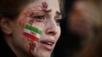 A demonstrator with an Iranian flag and bloody hands painted on her face attends a rally in support of the Iranian protests in Paris.