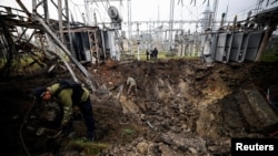 Investigators inspect a crater left by a Russian missile strike at an electrical transformer facility in Kharkiv in September 2022. 