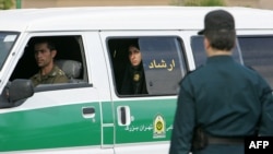 A female officer of Iran's morality police looks out of the back of a police vehicle during a crackdown to enforce the Islamic dress code in Tehran in 2007.