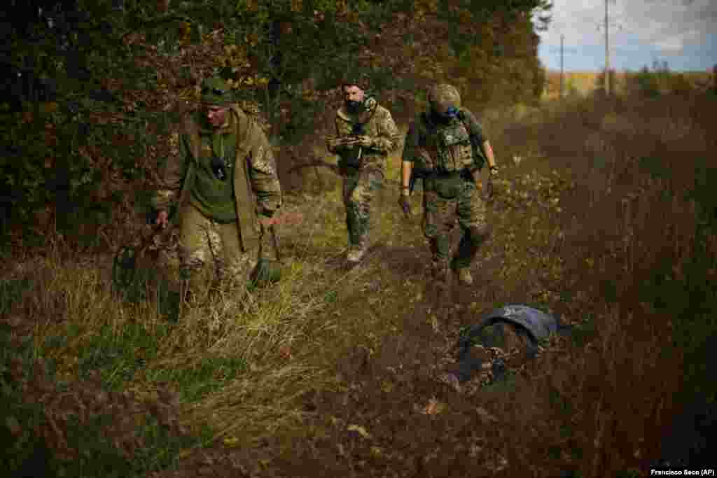 Ukrainian territorial defense members walk past the body of a local man reportedly killed by a Russian land mine.&nbsp;Hrakove village was home to around 1,000 people in February, when Russia launched its invasion of Ukraine. Only around 30 locals remained throughout the Russian occupation.&nbsp;