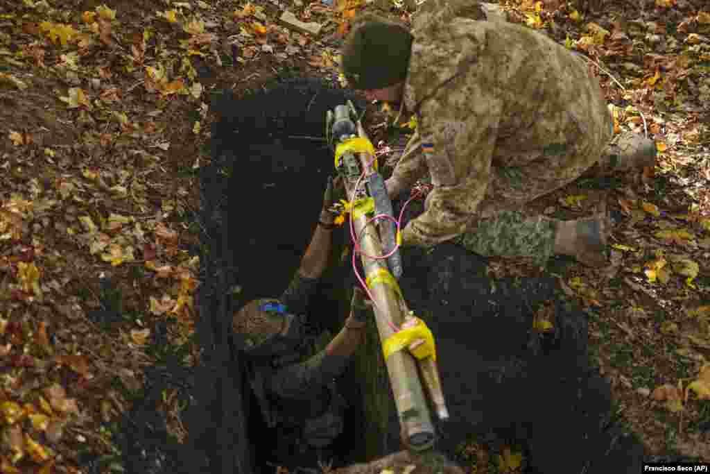 Ukrainian servicemen place Russian weapons and munitions into a deep hole to be destroyed as part of the ongoing cleanup of the areas recaptured by Ukrainian forces in the Kharkiv region.&nbsp;