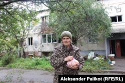 Елена Бубиенко стоит перед многоквартирным домом, в котором она сейчас живет, в Русских Тышках Харьковской области, Украина. 1 октября 2022 года