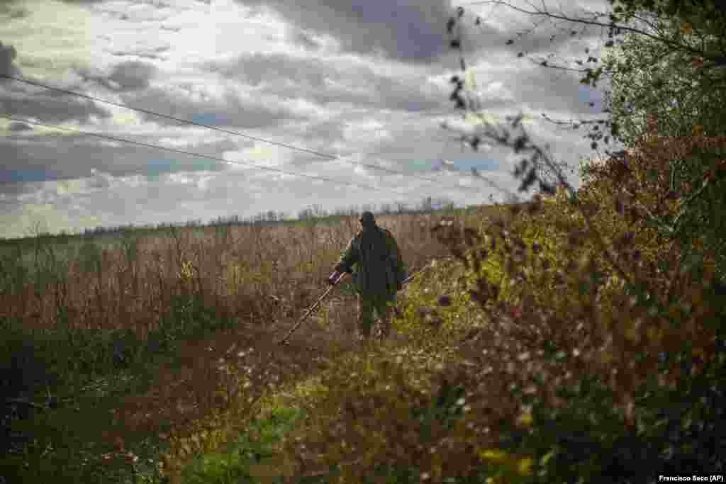 A Ukrainian territorial defense member checks for mines outside Hrakove village.&nbsp;