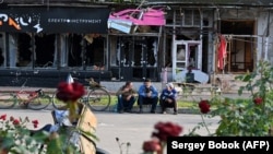 Local residents sit in front of damaged shops in Izyum on September 28, following liberation by Ukrainian forces.