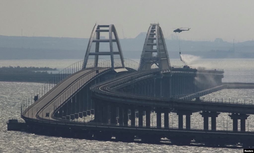 A helicopter drops water to extinguish fuel tanks ablaze on the Crimea Bridge on October 8.