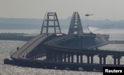 A helicopter drops water to extinguish fuel tanks ablaze on the Crimea Bridge on October 8.