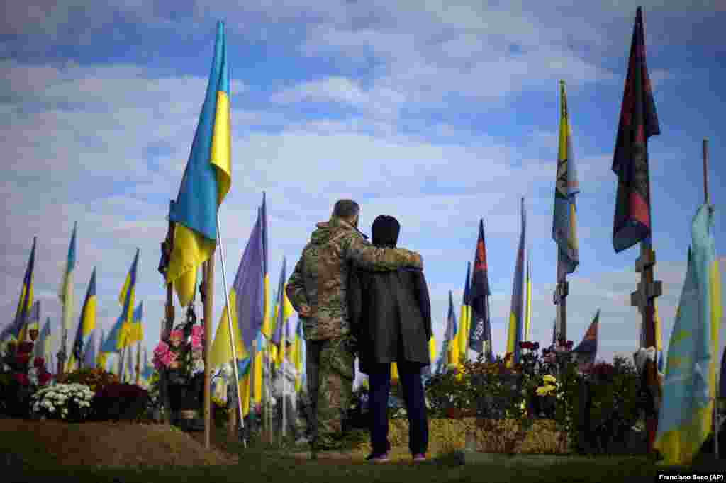 Parents of recently killed Ukrainian soldier, Ruslan Zhumaboev, stand next to his grave at a cemetery during Ukraine Defenders Day in Kharkiv on October 14.