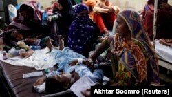 Women affected by the floods sit with their children suffering from malaria as they receive medical assistance at the Sayed Abdullah Shah Institute of Medical Sciences in Sehwan, Pakistan, on September 29.