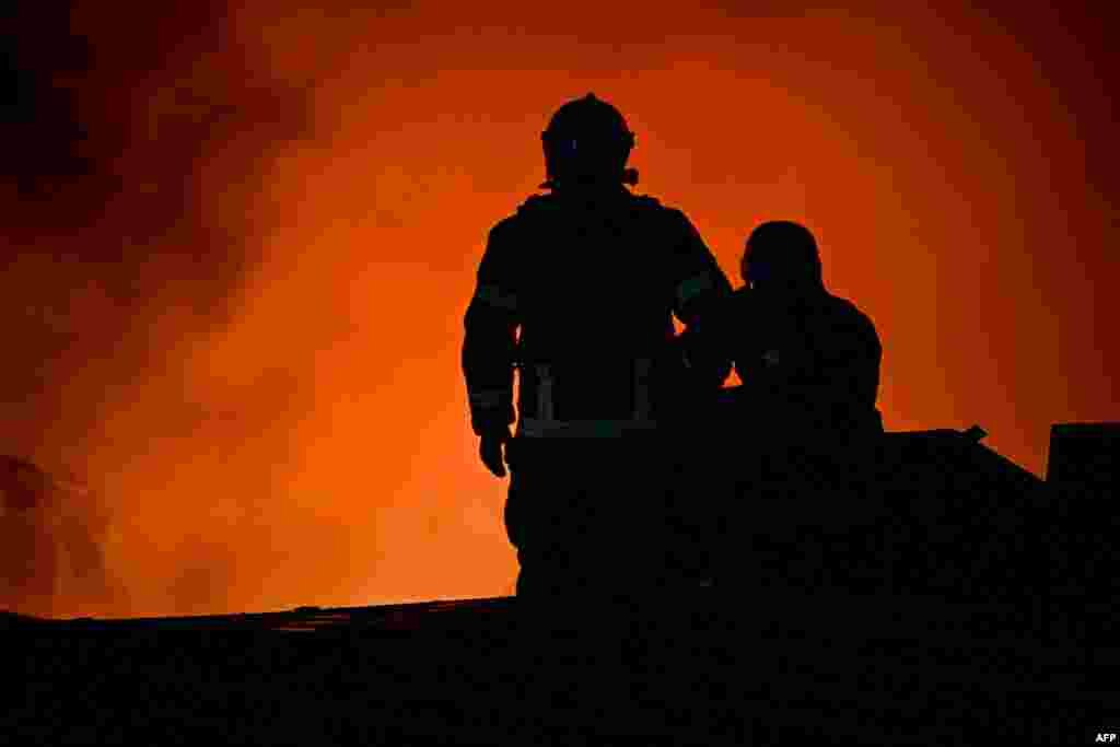 Ukrainian firefighters battle to save a railway freight depot in Kharkiv, which was partially destroyed by a Russian missile strike on September 27.