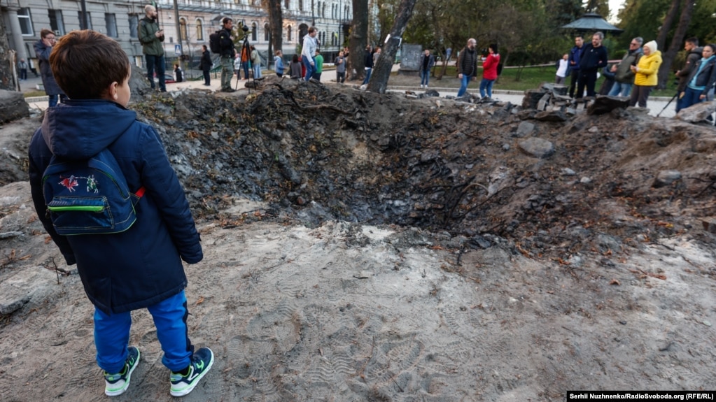 Një djalë i vogël duke shikuar një krater ku goditi një raketë pranë një sheshi lojërash në Parkun Taras Shevchenko në Kiev. Njerëzit më vonë vendosën lule në krater në shenjë nderimi për të vrarët gjatë sulmit.