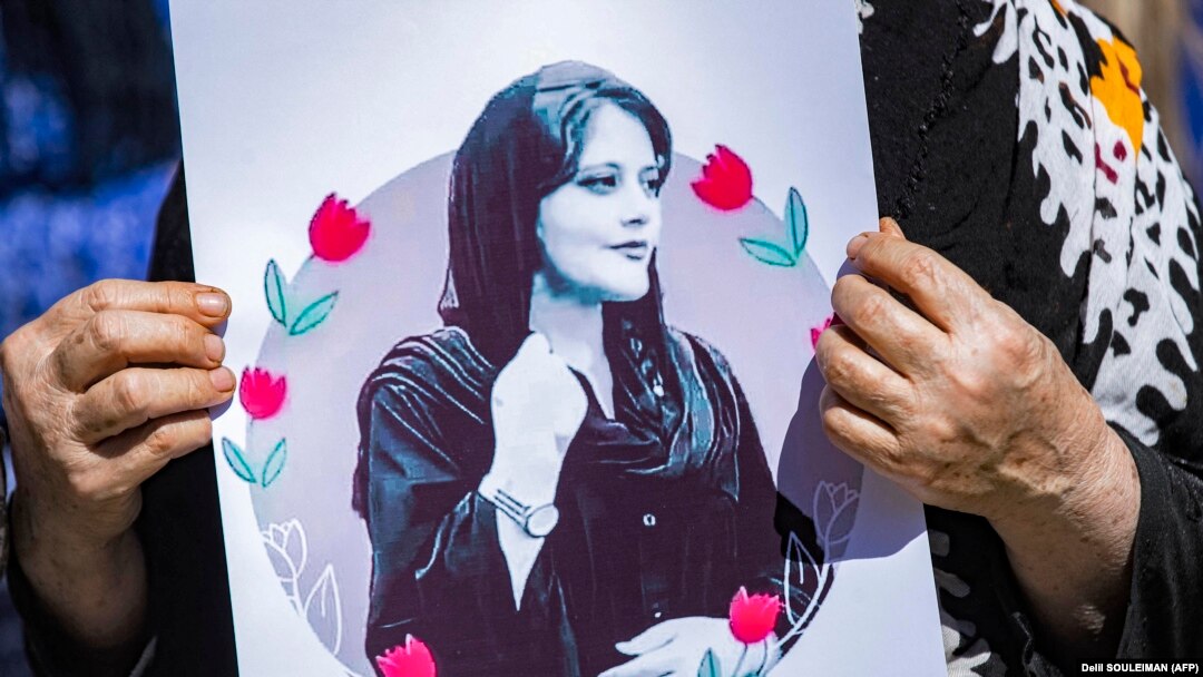 A woman holds a poster depicting Mahsa Amini during a protest following her death last year.