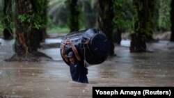Čovjek nosi prazan spremnik vode kroz poplavljeno područje nakon udara tropske oluje Julia, u Progresu, Honduras